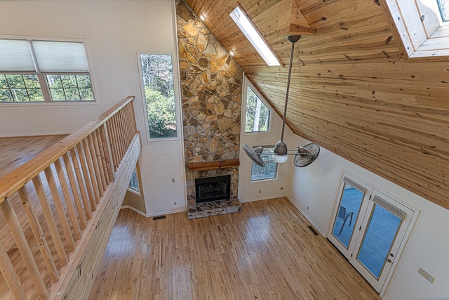 unfurnished living room featuring high vaulted ceiling, a fireplace, ceiling fan, wooden ceiling, and light wood-type flooring