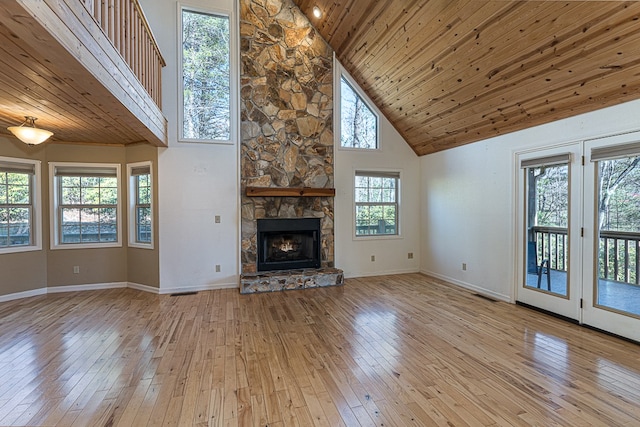 unfurnished living room with wooden ceiling, high vaulted ceiling, a fireplace, and light hardwood / wood-style floors