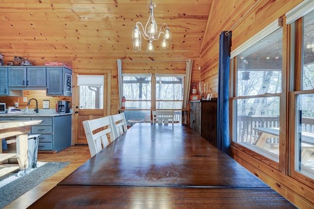 480 Sugar Mountain Rd, Blue Ridge, GA 30513 - unfurnished dining area with a wealth of natural light, light wood-style flooring, wood walls, and an inviting chandelier