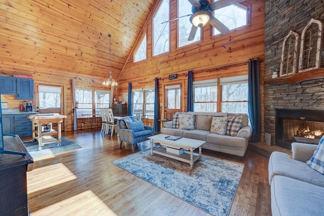 480 Sugar Mountain Rd, Blue Ridge, GA 30513 - living area featuring a fireplace, wood finished floors, wood walls, plenty of natural light, and ceiling fan with notable chandelier