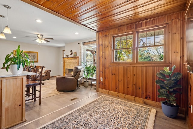 entryway featuring light hardwood / wood-style floors, wood walls, ceiling fan, and wood ceiling