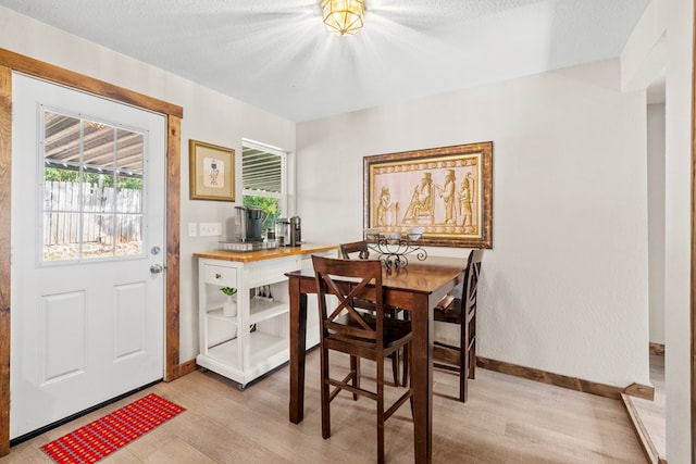 dining space with light wood-type flooring and a textured ceiling