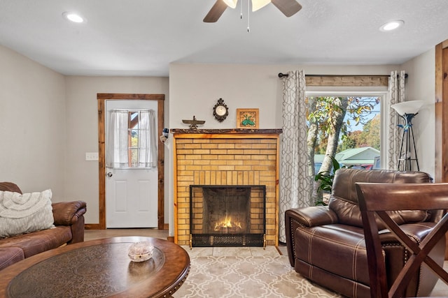 living room with a textured ceiling, ceiling fan, and a fireplace