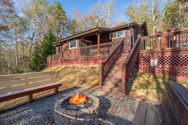 rear view of property with a deck and a fire pit