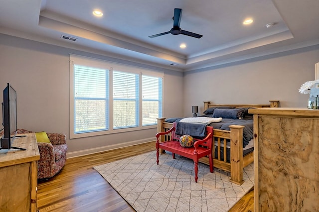 bedroom with a tray ceiling, light hardwood / wood-style flooring, and ceiling fan