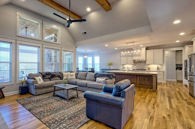 living room with ceiling fan with notable chandelier, beam ceiling, high vaulted ceiling, and light wood-type flooring