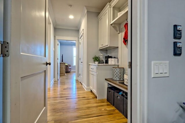 hallway with crown molding and light wood-type flooring