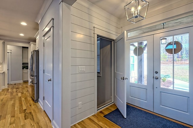 foyer entrance with plenty of natural light, wooden walls, light hardwood / wood-style floors, and french doors