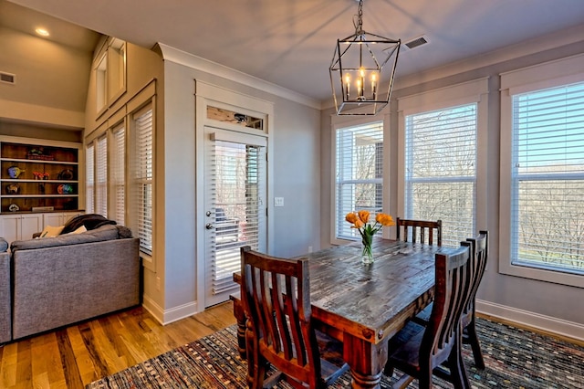 dining room with crown molding, an inviting chandelier, light hardwood / wood-style floors, and a wealth of natural light