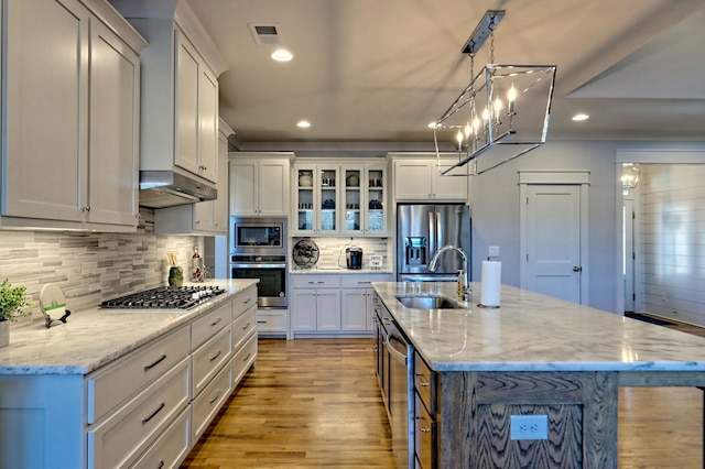 kitchen with a kitchen island with sink, sink, white cabinets, and appliances with stainless steel finishes