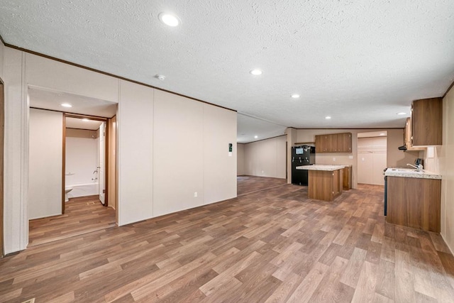 220 Jetty Dr, Ellijay, GA 30540 - kitchen featuring brown cabinetry, freestanding refrigerator, light wood finished floors, a textured ceiling, and open floor plan