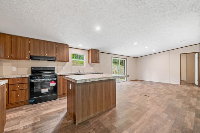220 Jetty Dr, Ellijay, GA 30540 - kitchen with black range with gas stovetop, under cabinet range hood, light wood-type flooring, brown cabinetry, and a textured ceiling