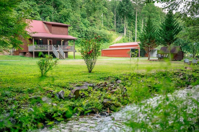 view of yard with covered porch and a wooded view