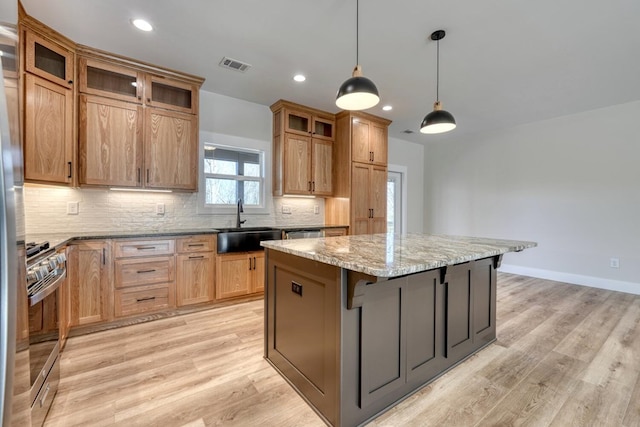 kitchen featuring a kitchen island, light stone counters, a kitchen breakfast bar, stainless steel stove, and pendant lighting