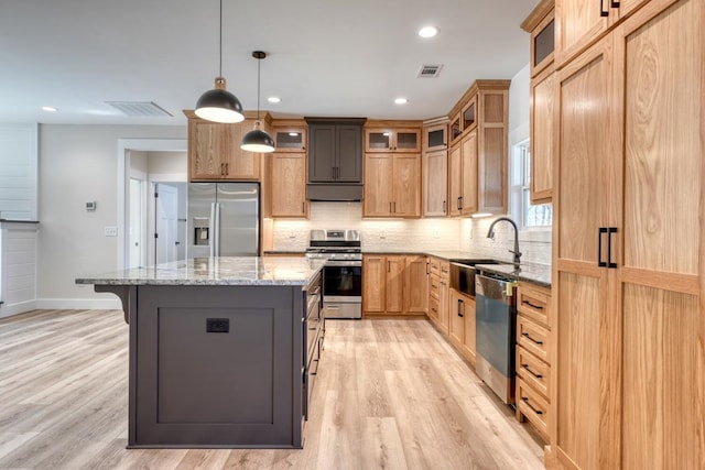 kitchen featuring light stone counters, decorative light fixtures, stainless steel appliances, visible vents, and a kitchen island