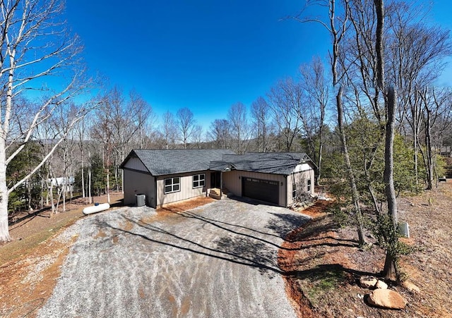 single story home featuring a garage, driveway, and roof with shingles