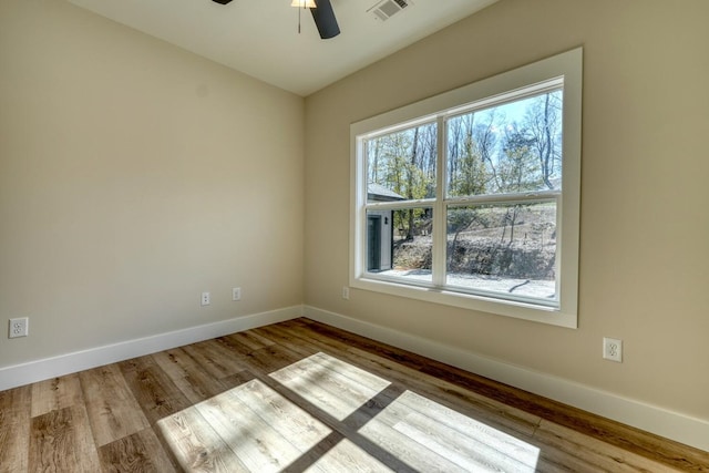 spare room featuring ceiling fan, light wood-type flooring, visible vents, and baseboards