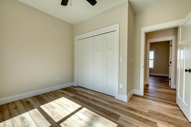 unfurnished bedroom with light wood-style floors, ceiling fan, baseboards, and a closet