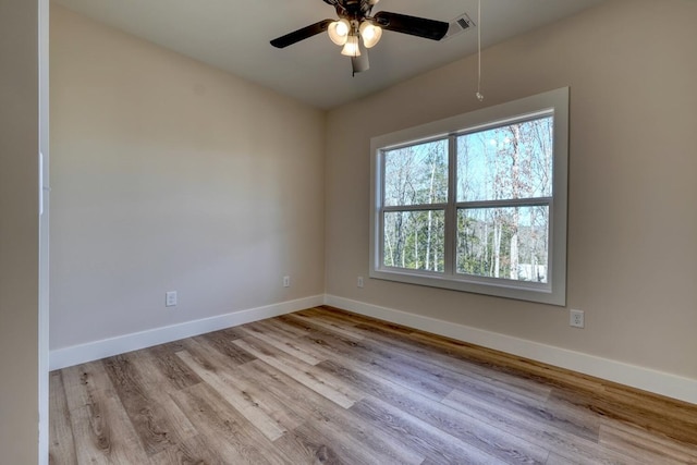 spare room featuring visible vents, a ceiling fan, baseboards, light wood-type flooring, and attic access