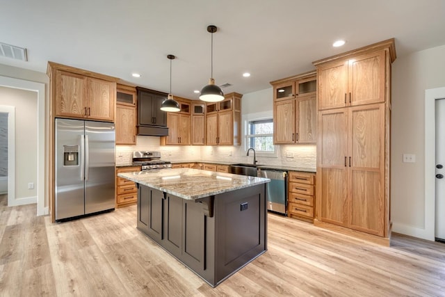 kitchen featuring light stone counters, a center island, stainless steel appliances, visible vents, and hanging light fixtures