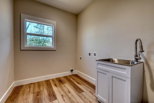 laundry area with cabinet space, hookup for an electric dryer, light wood-style floors, washer hookup, and a sink