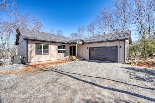 view of front facade featuring driveway, an attached garage, central AC unit, and roof with shingles