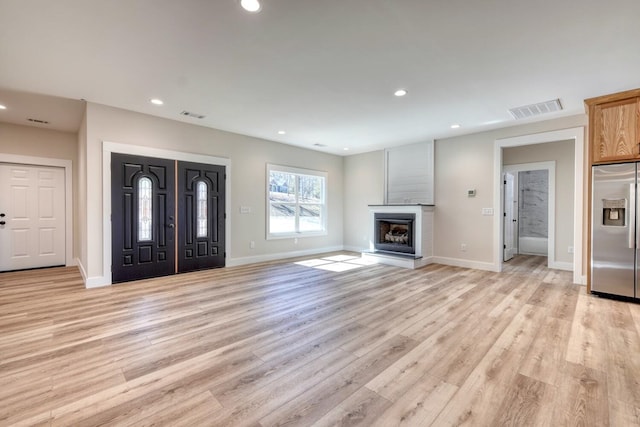 interior space featuring a glass covered fireplace, visible vents, and recessed lighting