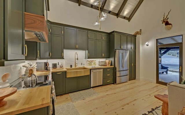 kitchen featuring appliances with stainless steel finishes, green cabinetry, wood counters, high vaulted ceiling, and sink