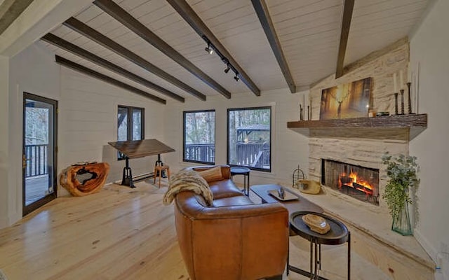 living room with light hardwood / wood-style floors, track lighting, a large fireplace, and vaulted ceiling with beams