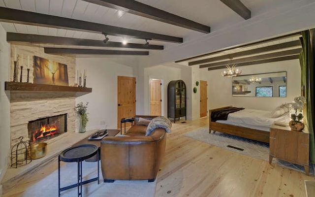 bedroom with a fireplace, light hardwood / wood-style floors, a chandelier, and beam ceiling