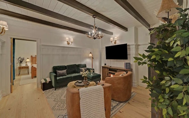 living room featuring light hardwood / wood-style floors, beam ceiling, and an inviting chandelier