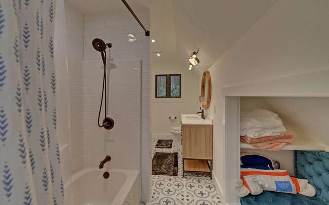 full bathroom with toilet, vanity, tiled shower / bath, and lofted ceiling