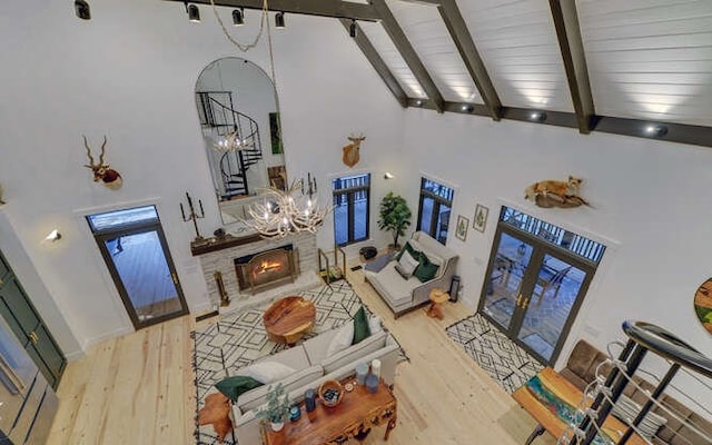 living room with high vaulted ceiling, beamed ceiling, a stone fireplace, and hardwood / wood-style floors