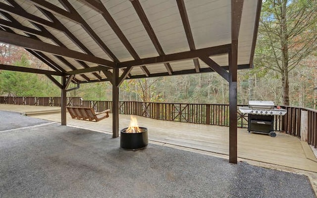 wooden deck featuring area for grilling and a fire pit