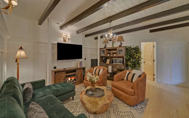 7670 Hiawassee Wilderness, Hiawassee, GA 30546 - living room with a decorative wall, a chandelier, beam ceiling, wood finished floors, and a warm lit fireplace