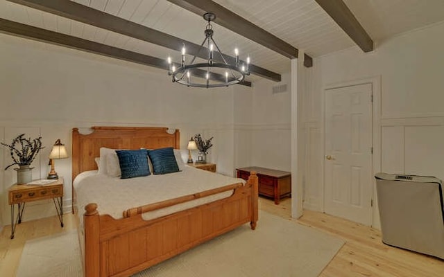 bedroom featuring a chandelier, light hardwood / wood-style floors, and beam ceiling