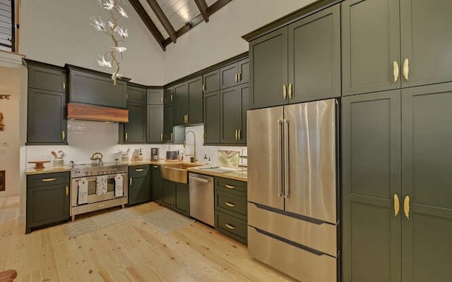 kitchen featuring range hood, appliances with stainless steel finishes, high vaulted ceiling, sink, and light hardwood / wood-style flooring