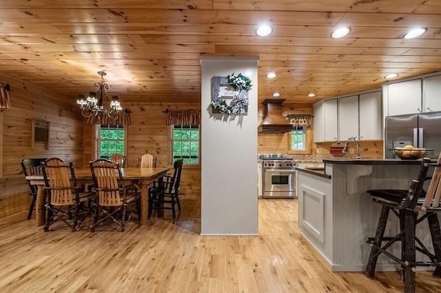 608 Pine Pass Cir, Mineral Bluff, GA 30559 - kitchen with stainless steel range, premium range hood, dark countertops, light wood-type flooring, and a breakfast bar