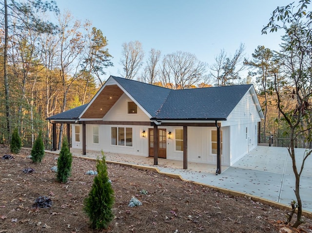 modern inspired farmhouse with a shingled roof, a patio, and board and batten siding