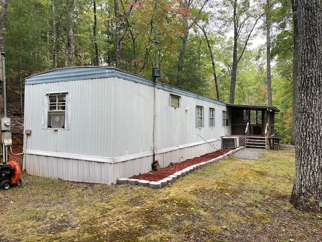 view of side of home with cooling unit and a yard