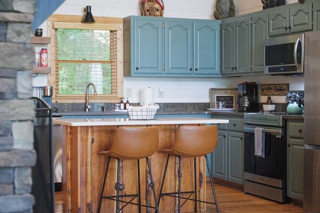 437 Spruce Cir, Mineral Bluff, GA 30559 - kitchen with appliances with stainless steel finishes, a sink, a kitchen bar, a center island, and light wood-style flooring