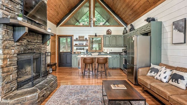 437 Spruce Cir, Mineral Bluff, GA 30559 - living room with wood ceiling, light wood-style flooring, a stone fireplace, vaulted ceiling, and wood walls