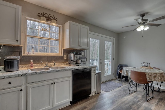 kitchen with black dishwasher, a wealth of natural light, backsplash, a sink, and wood finished floors