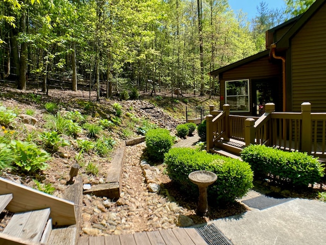 view of yard featuring a wooden deck and a wooded view