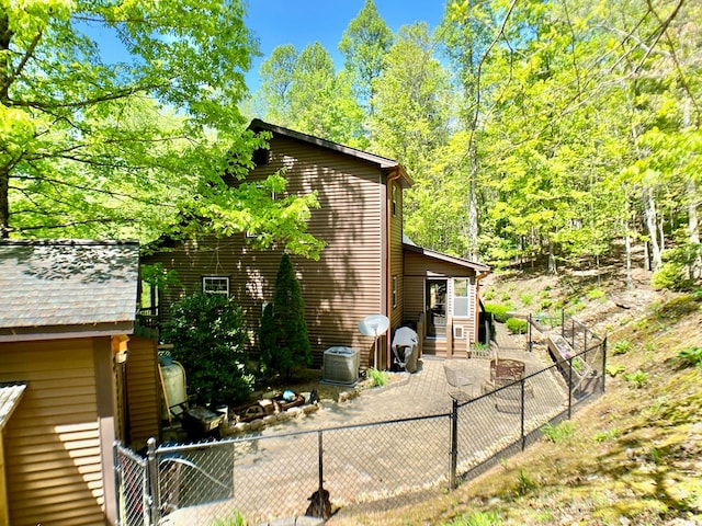 view of side of property featuring central air condition unit, a gate, a fenced backyard, and a patio area