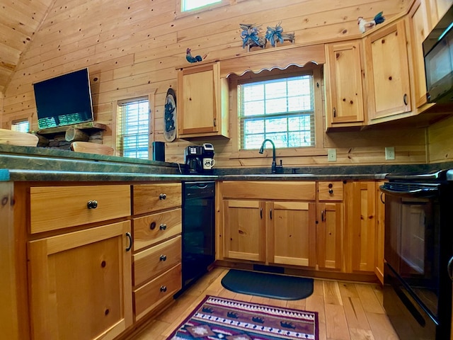 kitchen with dark countertops, vaulted ceiling, a sink, black appliances, and light wood-style flooring