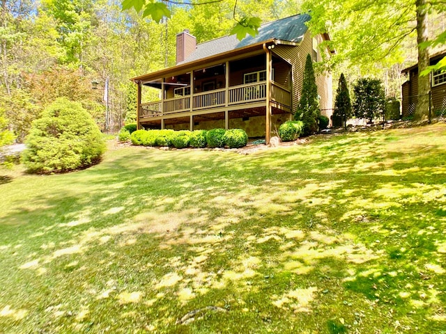 rear view of property featuring a yard, a chimney, and roof with shingles