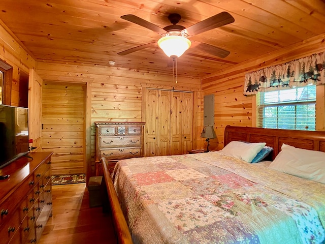 bedroom featuring ceiling fan, wood walls, wooden ceiling, and wood finished floors