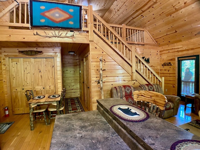 interior space with wooden walls, wood-type flooring, high vaulted ceiling, wood ceiling, and stairway