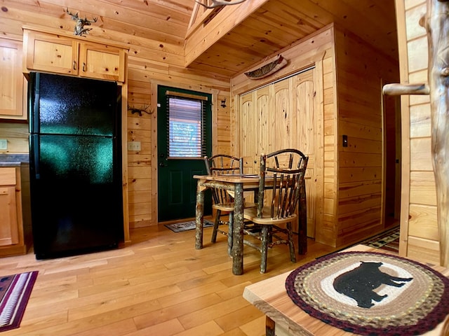 dining room featuring light wood-type flooring, wooden walls, and wooden ceiling